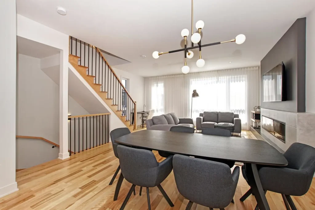 Salle à manger et salon lumineux avec escalier moderne, intérieur de Maison de ville à Laval au design épuré.