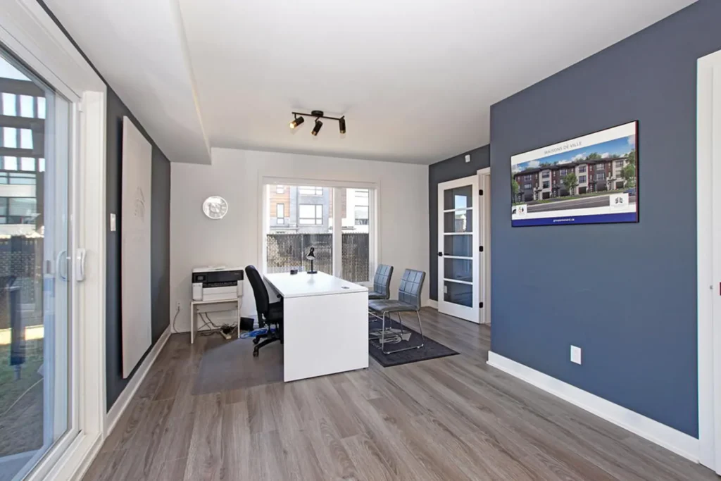 Bureau moderne lumineux avec mobilier minimaliste, murs gris et bleus, grande fenêtre, maison de ville à Laval