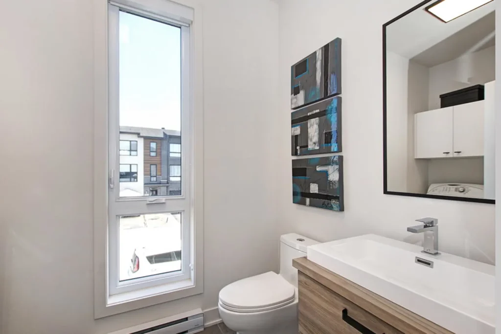Salle de bain moderne lumineuse avec vanité en bois, grande fenêtre et déco murale, Maison de ville à Laval
