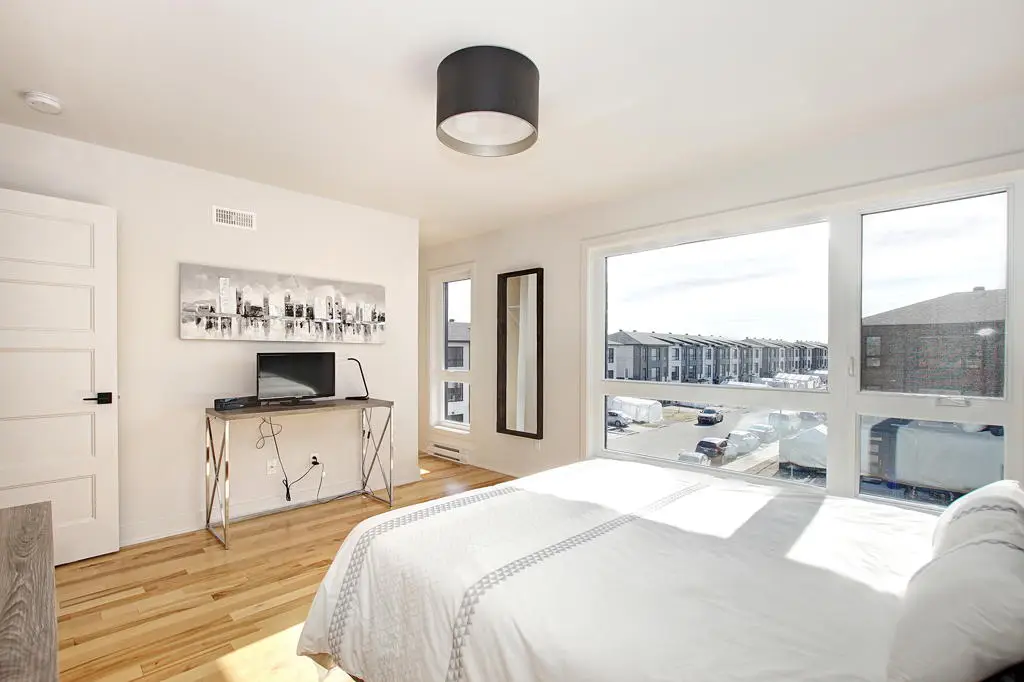 Chambre moderne lumineuse avec grandes fenêtres et vue sur des rangées de Maison de ville à Laval