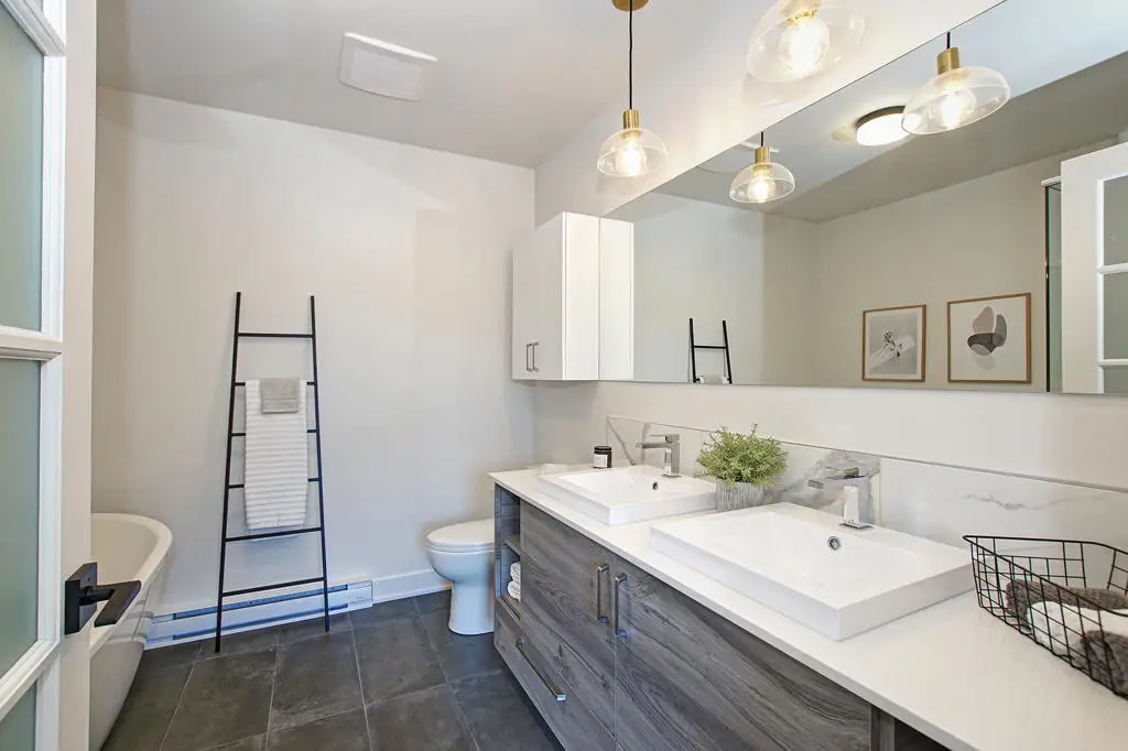 Salle de bain moderne avec double vasque, baignoire et éclairage suspendu, maison de ville à Laval