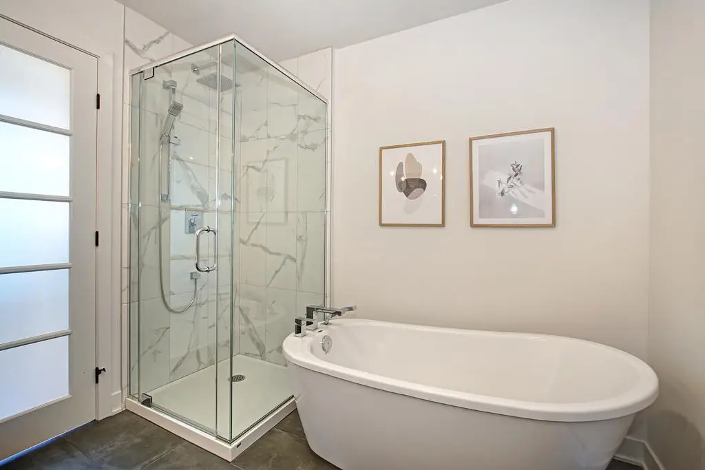 Salle de bain moderne avec douche vitrée, bain autoportant et finitions marbre, Maison neuves à Laval