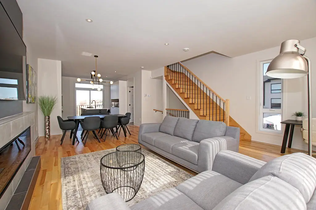 Salon et salle à manger ouverts avec escalier en bois dans une maison de ville à Laval lumineuse et moderne