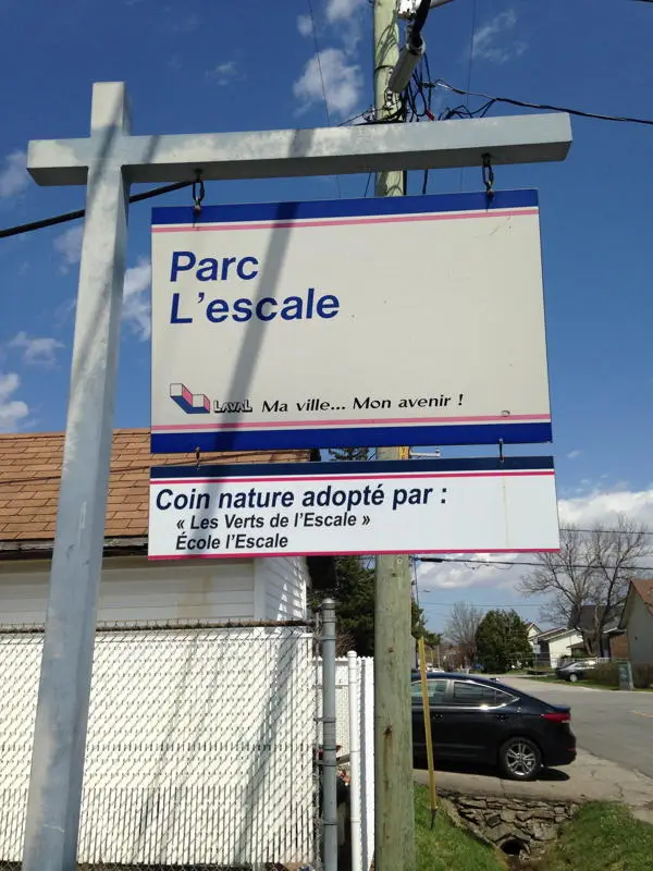 Panneau du parc L’Escale à Laval, installé au coin d’une rue résidentielle sous ciel bleu