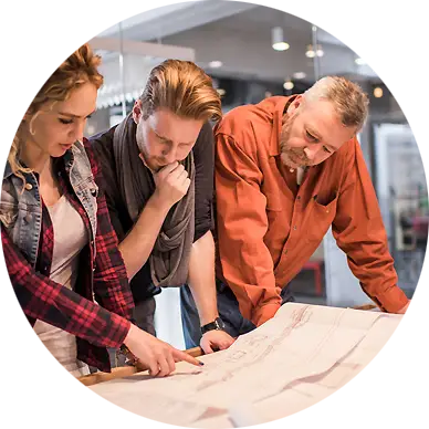 Trois professionnels penchés sur des plans d’architecture pour un projet de maisons de ville neuves