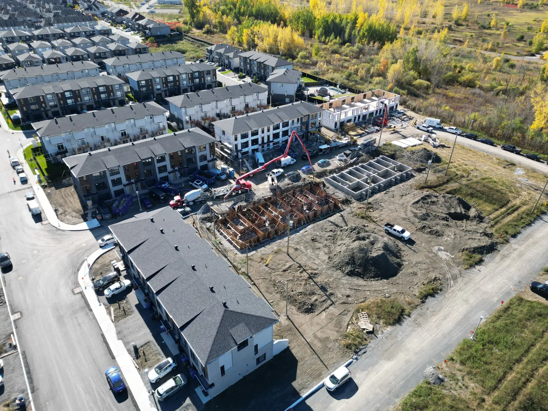 Vue aérienne d’un projet de maisons de ville neuves à Laval en chantier avec fondations et rangées d’habitations modernes.